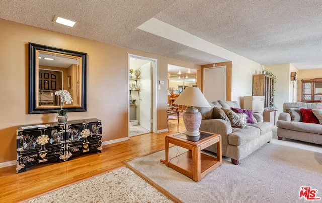 a living room with furniture and a large mirror next to a window