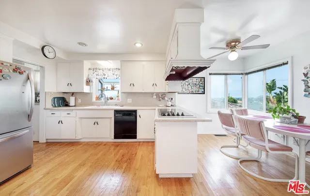 a kitchen with stainless steel appliances a stove a sink dishwasher a refrigerator cabinets and wooden floor