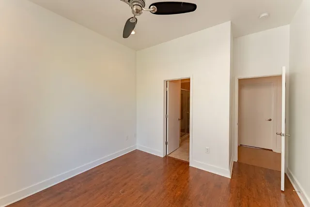 a view of a hallway with wooden floor and a bathroom