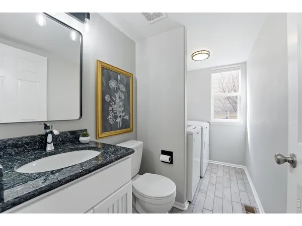 a bathroom with a granite countertop sink toilet and a mirror