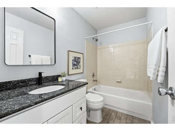 a bathroom with a granite countertop sink a mirror a bathtub and shower