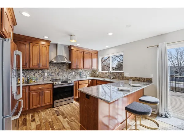 a kitchen with stainless steel appliances granite countertop a stove top oven a sink dishwasher and cabinets with wooden floor