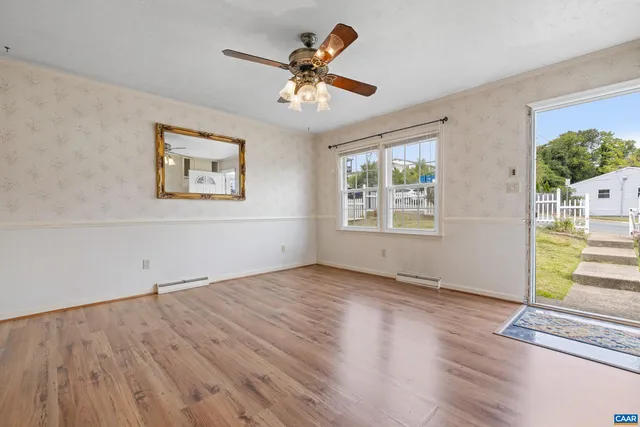 a view of empty room with wooden floor and fan