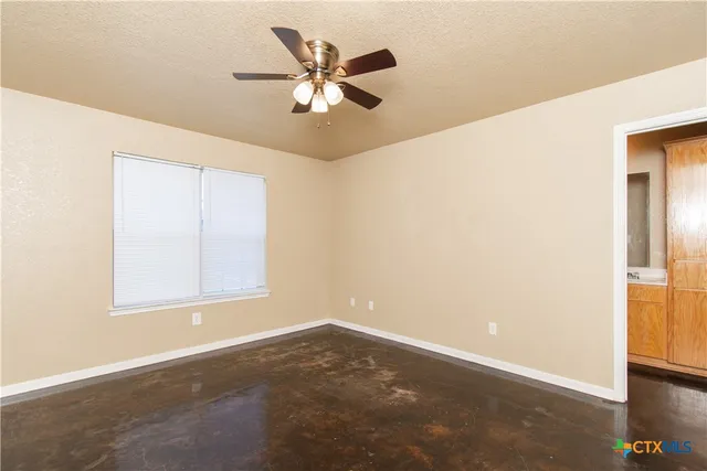 an empty room with a window and a ceiling fan