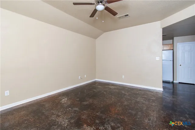 an empty room with a ceiling fan and carpet
