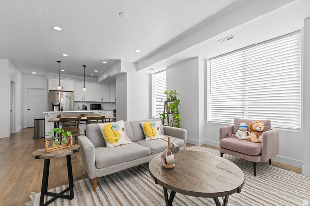 8307 Durham Street Sandy, UT 84070 - Photo 4 of 29 Open-concept living area featuring wood-finish flooring, recessed lighting, and large windows with white blinds