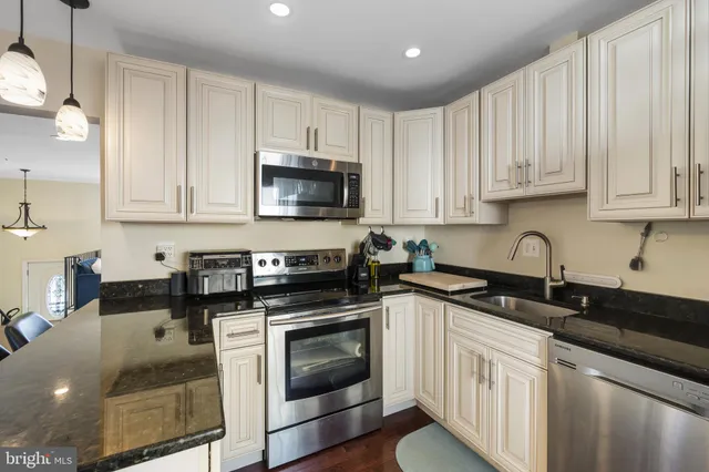 a kitchen with stainless steel appliances granite countertop a sink a stove a microwave and cabinets