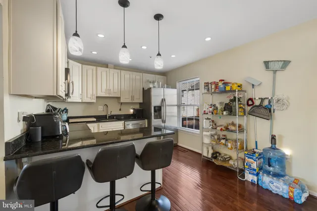 a kitchen with stainless steel appliances granite countertop a refrigerator a stove a sink dishwasher and a dining table with wooden floor