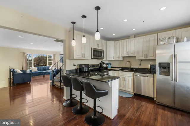 a kitchen with stainless steel appliances granite countertop a refrigerator a sink dishwasher a stove and white cabinets with wooden floor