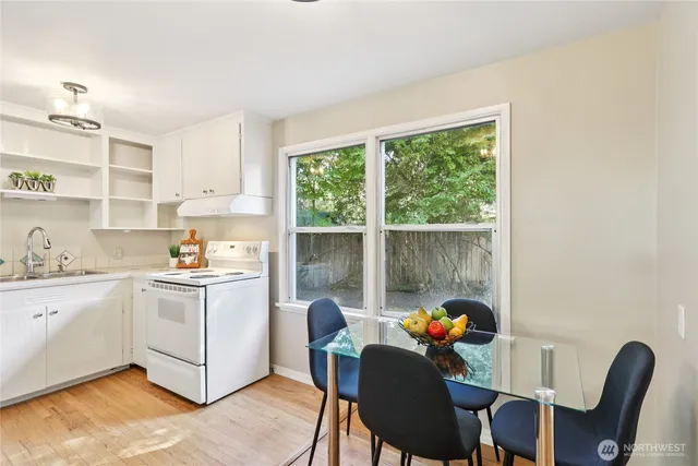 a kitchen with stainless steel appliances granite countertop a stove a refrigerator a dining table and chairs next to a window