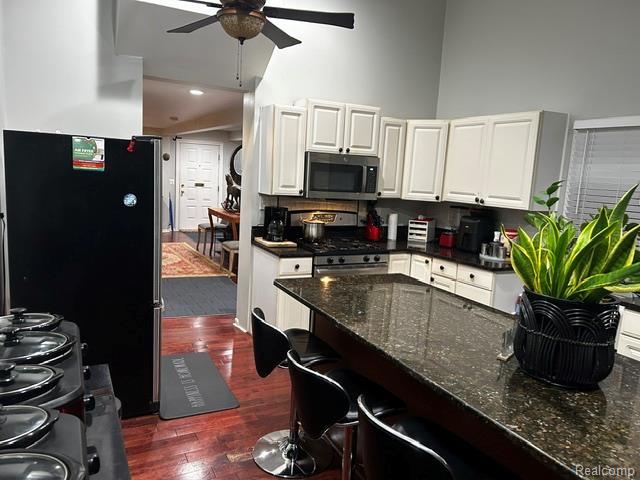 89 Muir Road Grosse Pointe, MI 48236 - Photo 16 of 29 Kitchen featuring white cabinetry, dark speckled countertops, stainless steel appliances, and wood-finish flooring