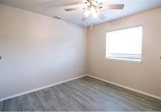 an empty room with a window and a fan