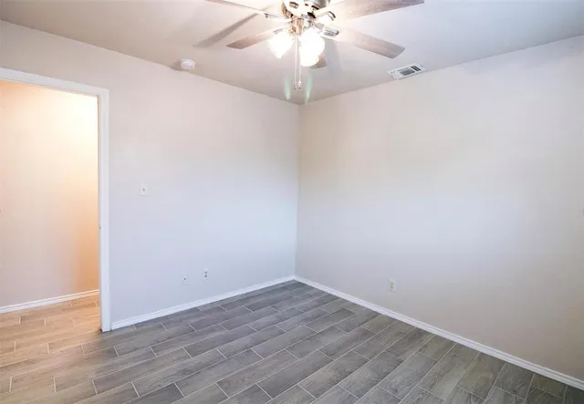 an empty room with wooden floor and fan