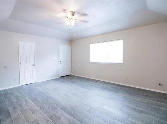 an empty room with wooden floor and windows