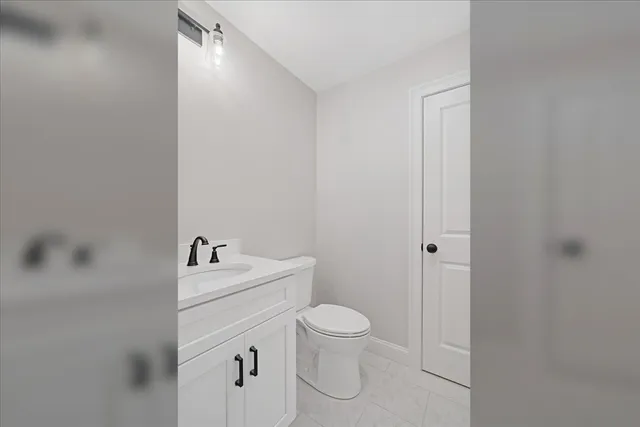 a bathroom with a toilet a sink a mirror and vanity