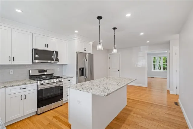 a kitchen with stainless steel appliances kitchen island granite countertop a stove a sink and a refrigerator