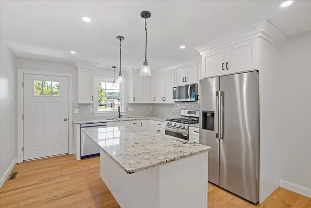 a kitchen with stainless steel appliances granite countertop a refrigerator a sink a stove and a wooden floors