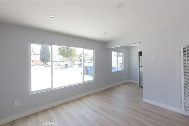 a view of an empty room with a window and wooden floor