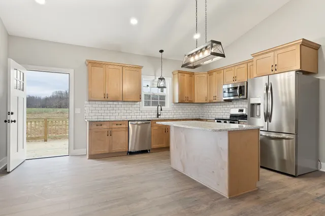 a kitchen with stainless steel appliances granite countertop a refrigerator a stove a sink dishwasher and a refrigerator with wooden floor