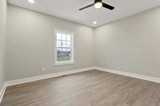 an empty room with wooden floor fan and window