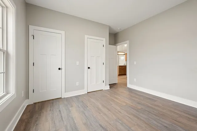 a view of an empty room with wooden floor and window