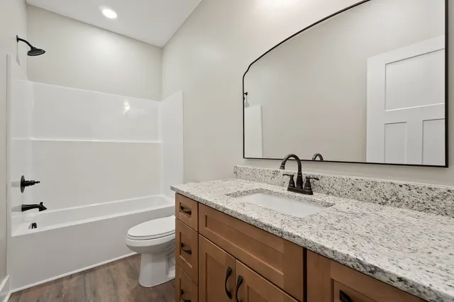 a bathroom with a granite countertop sink a toilet and shower
