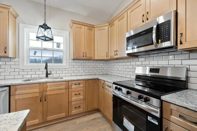 a kitchen with cabinets appliances a sink and a window