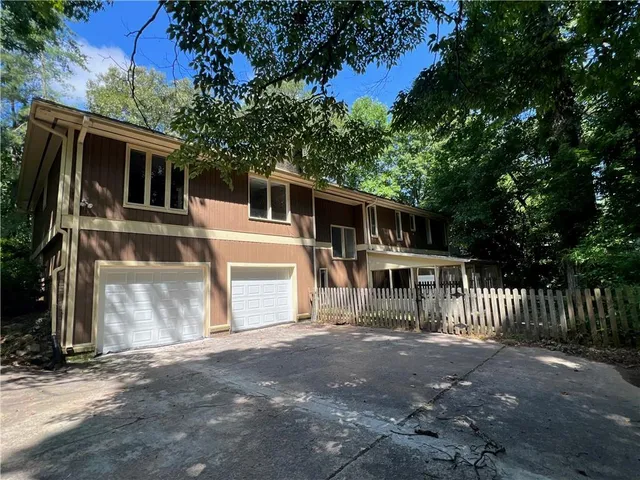 a view of house with a yard and large trees