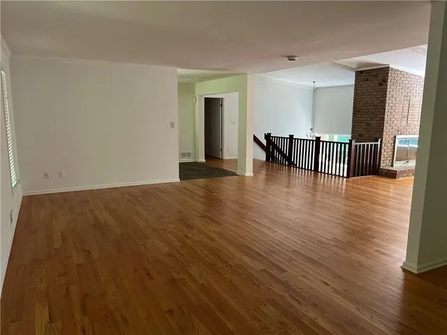a view of an empty room with wooden floor and a large window
