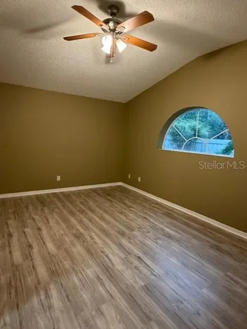 a view of empty room with ceiling fan and window