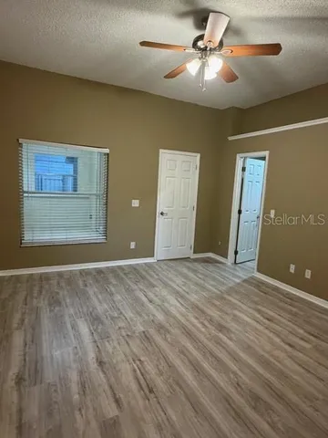 an empty room with wooden floor and fan