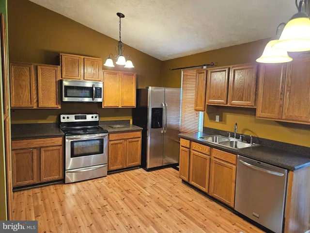 a kitchen with granite countertop a stove top oven microwave and refrigerator