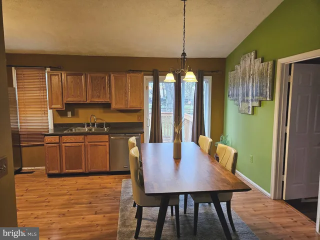 a kitchen with stainless steel appliances granite countertop a kitchen island hardwood floor sink stove dining table and chairs