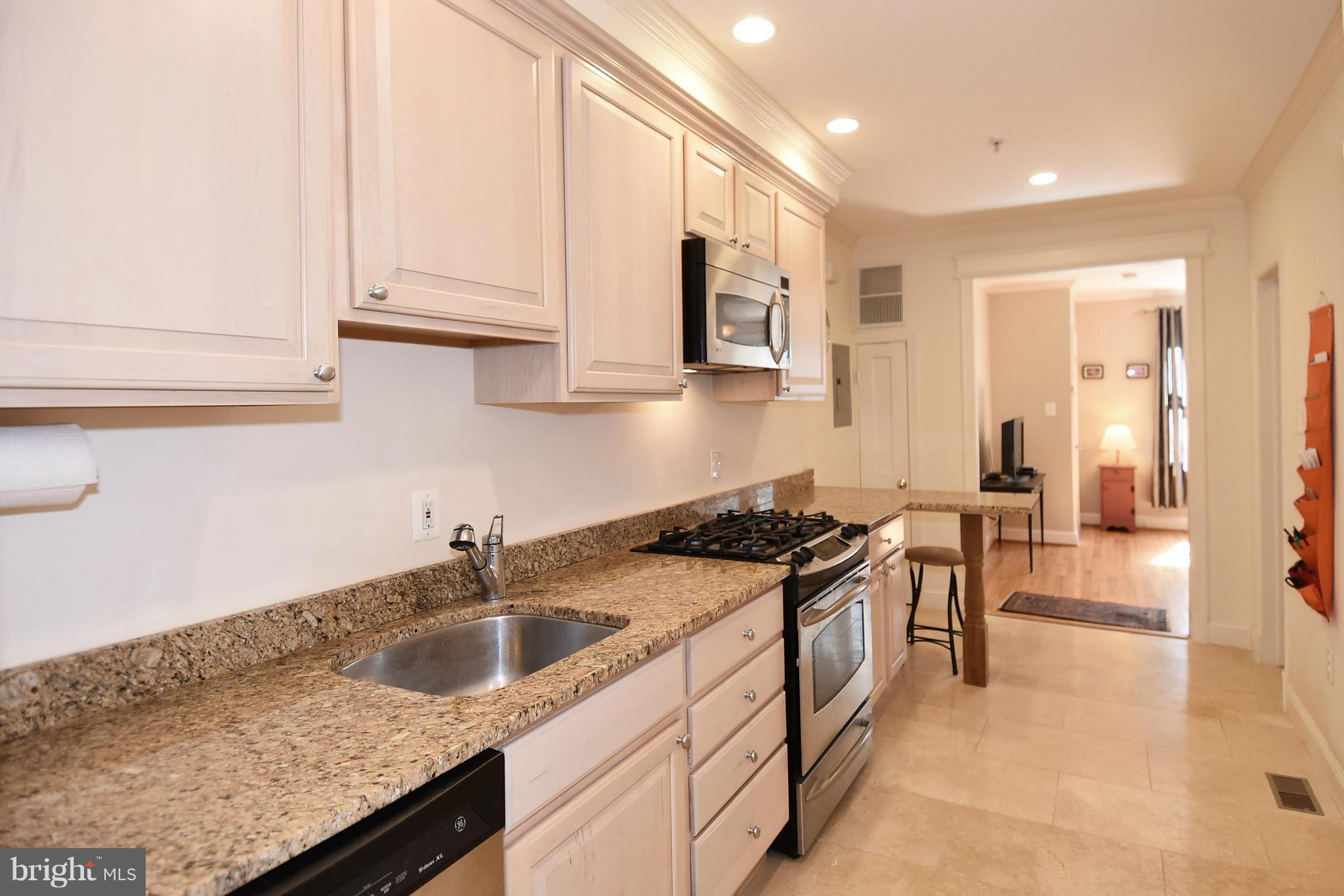4010 Kansas Avenue Northwest, Unit 1 Washington, DC 20011 - Photo 8 of 28 a kitchen with granite countertop a sink a stove and cabinets