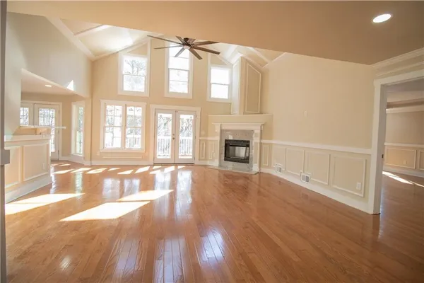 a view of an empty room with window and wooden floor