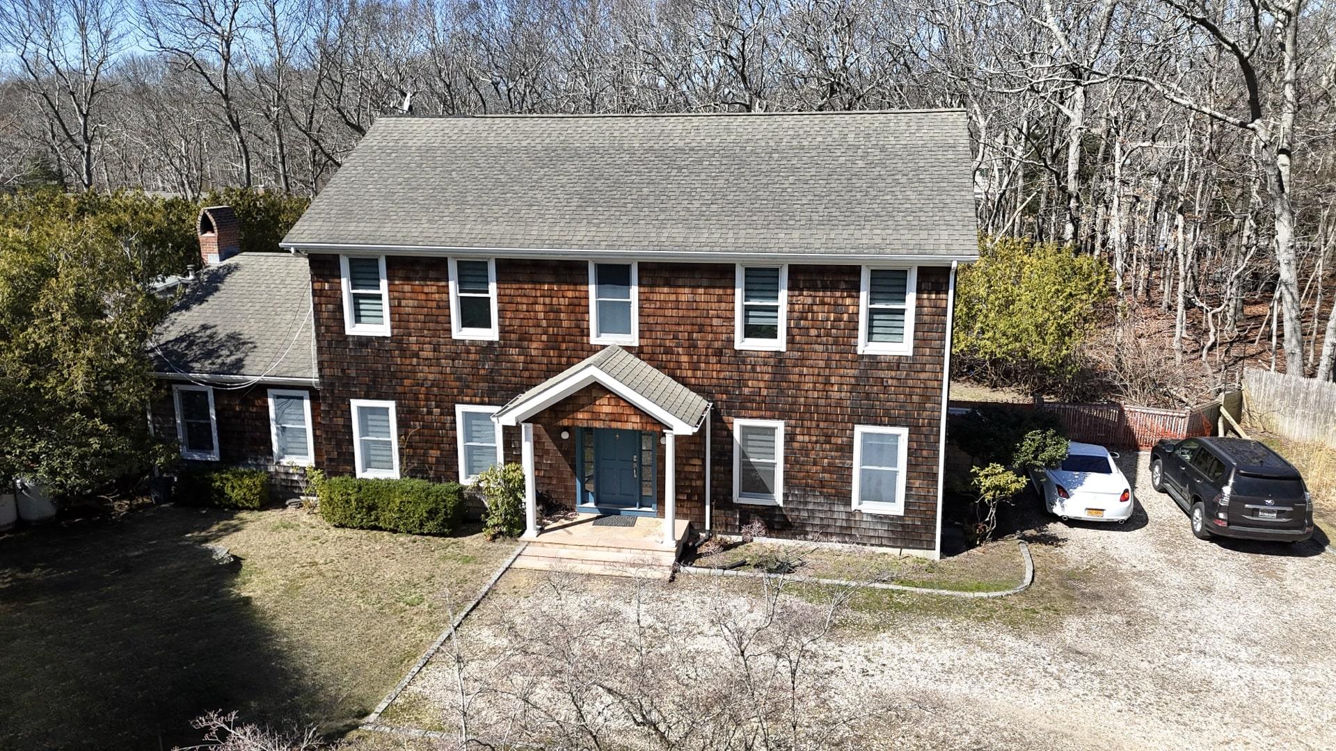 Colonial home featuring fence, a front lawn, roof with shingles, and a chimney