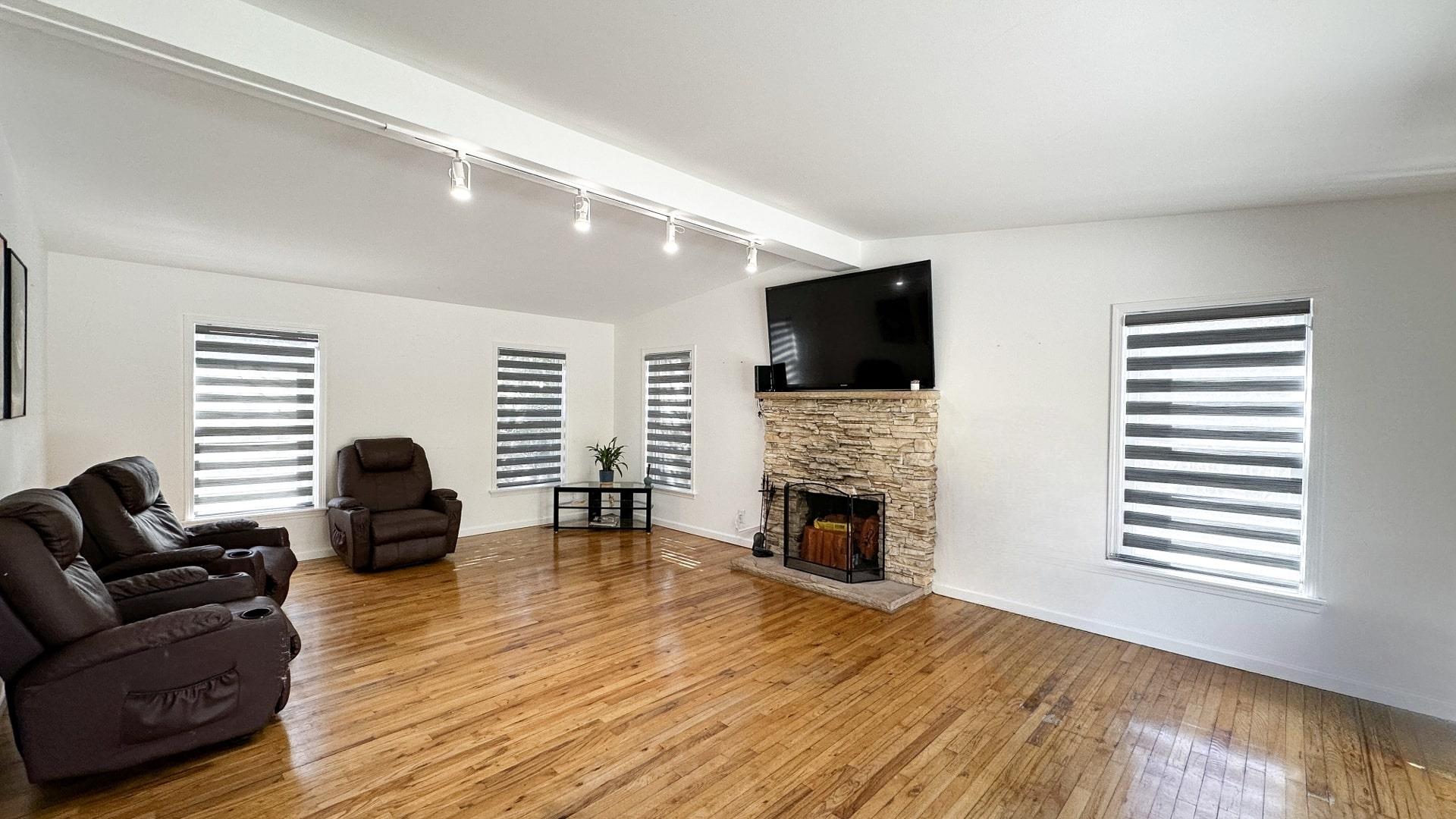39 Washington Avenue East Hampton, NY 11937 - Photo 9 of 21 Living room with light wood-style flooring, track lighting, baseboards, a stone fireplace, and lofted ceiling