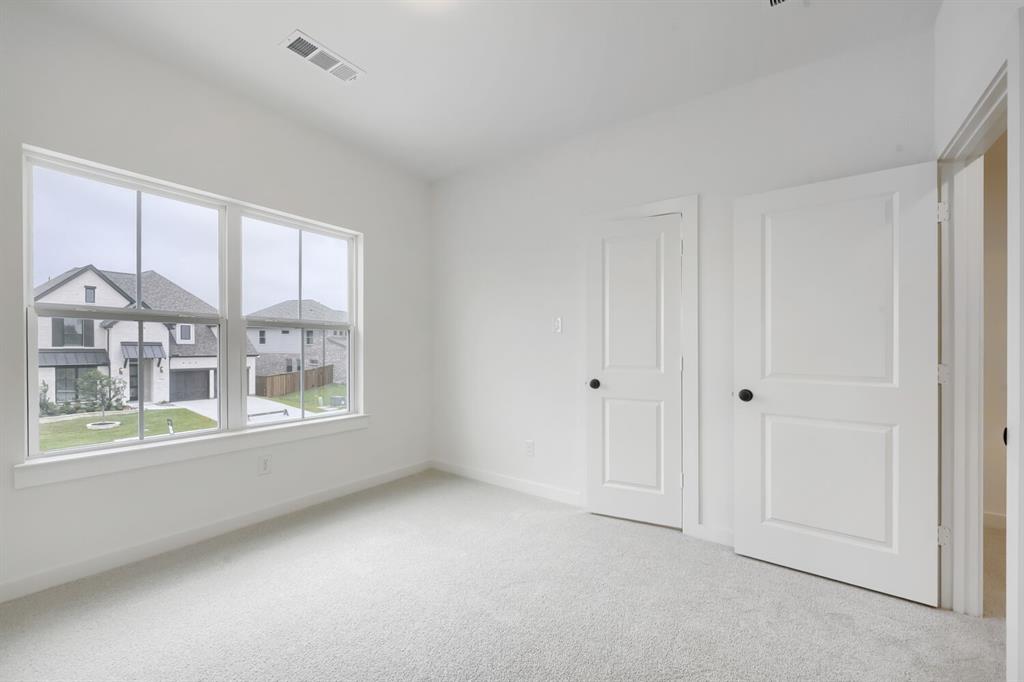 733 Red Cedar Road Haslet, TX 76052 - Photo 18 of 28 Bright room featuring light gray carpeting, a large multipane window, white trim, two white two-panel doors with black hardware, and an overhead ventilation register