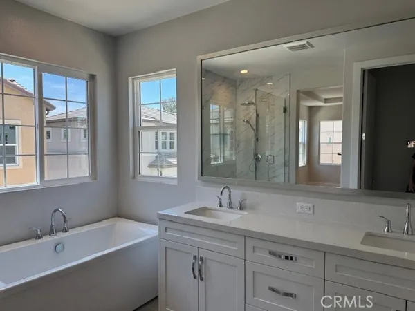 a bathroom with a tub a sink double vanity and window