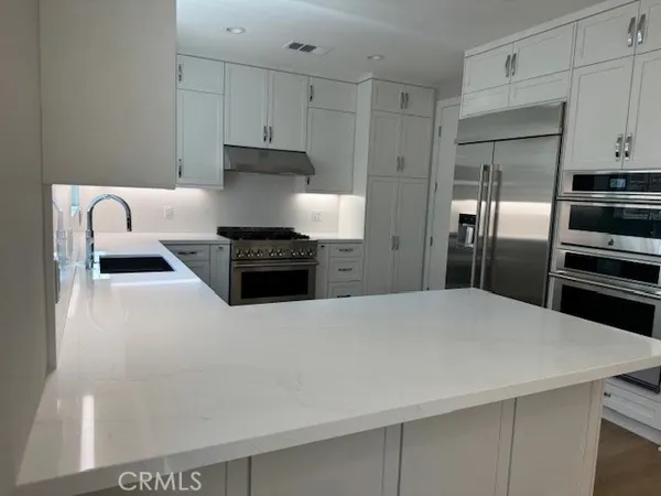 a kitchen with stainless steel appliances a refrigerator a stove and white cabinets