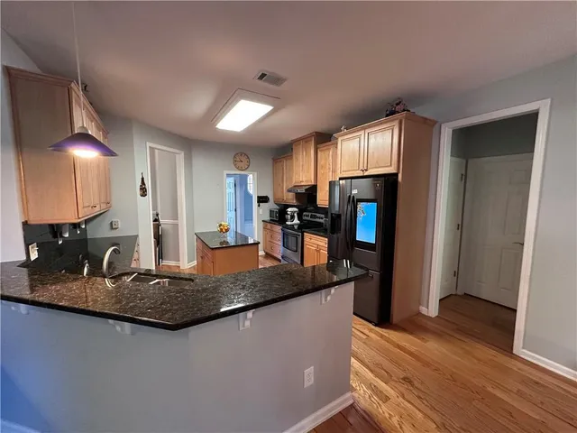 a kitchen with stainless steel appliances granite countertop a sink refrigerator and cabinets
