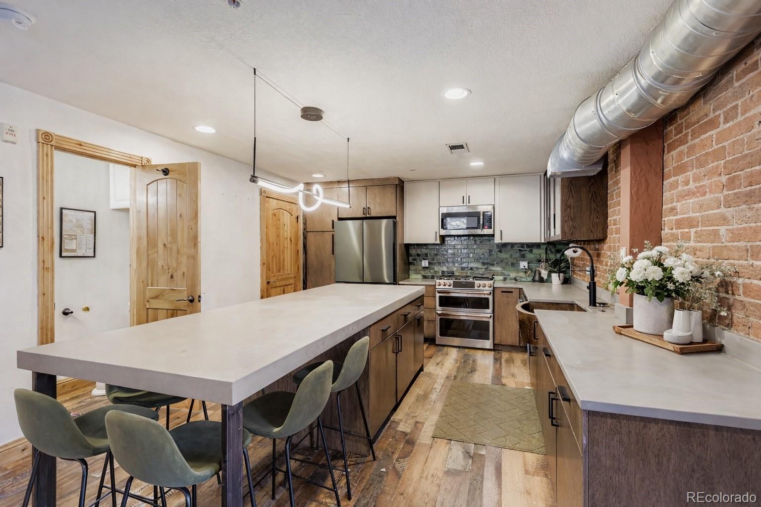 3033 Blake Street, Unit 109 Denver, CO 80205 - Photo 12 of 43 a kitchen with a table chairs refrigerator and microwave