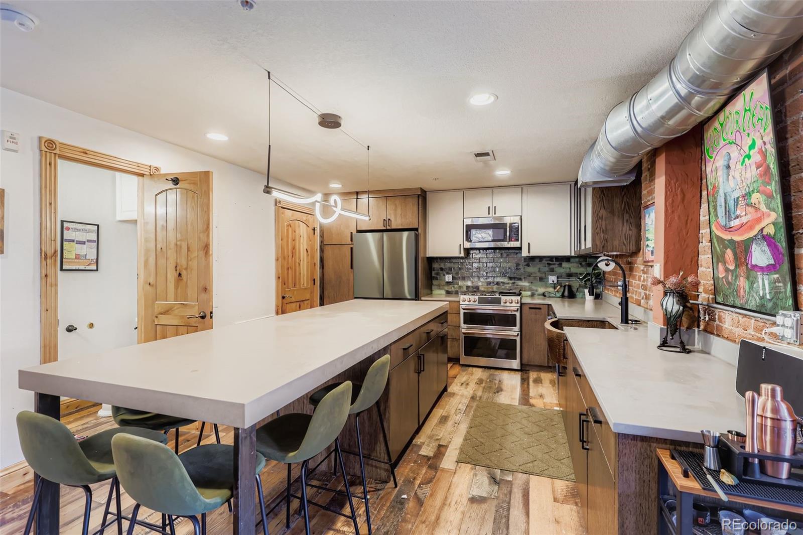 3033 Blake Street, Unit 109 Denver, CO 80205 - Photo 30 of 43 a kitchen with stainless steel appliances granite countertop a stove a refrigerator a kitchen island a sink and chairs