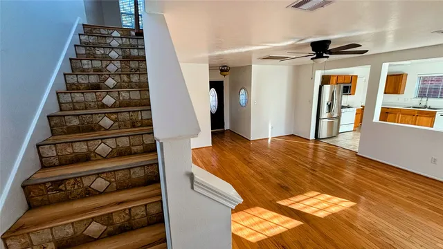 a view of empty room with wooden floor and fan
