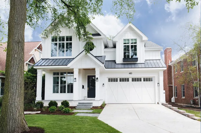 a view of a white house next to a yard with plants and trees