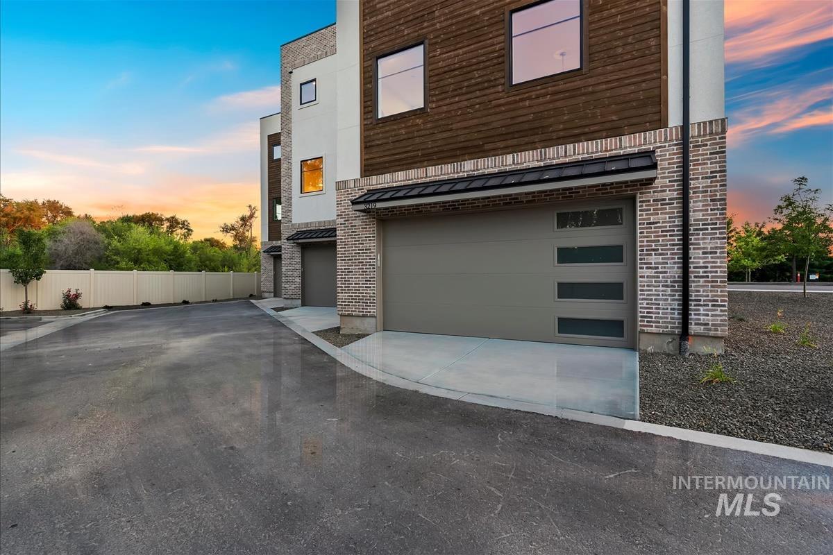 3219 West Moore Street Boise, ID 83702 - Photo 33 of 36 Contemporary exterior featuring brick and horizontal wood paneling, modern garage doors with frosted glass panels, and a concrete driveway