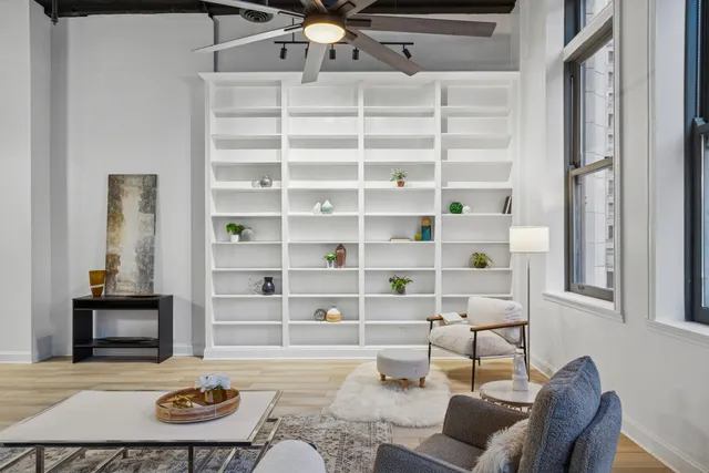 a living room with furniture large window and wooden floor