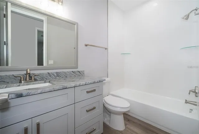 a bathroom with a granite countertop toilet a sink and a bathtub