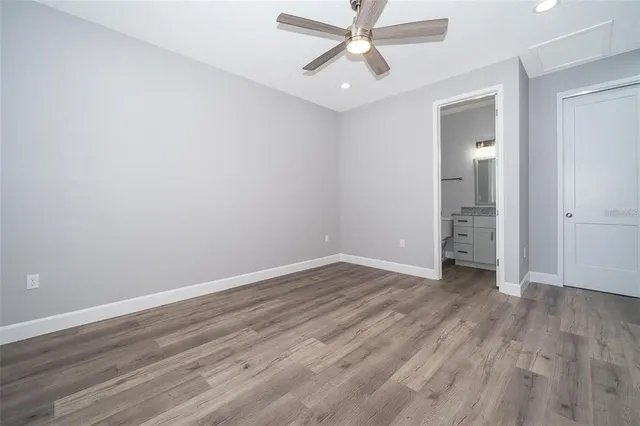 an empty room with wooden floor closet and windows