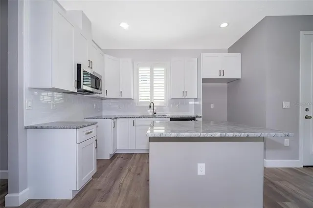 a kitchen with stainless steel appliances granite countertop a sink a stove top oven a counter space and cabinets